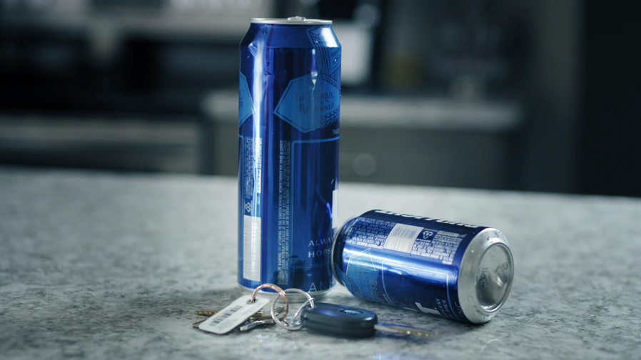 Two open beer cans next to a set of keys representing open container law