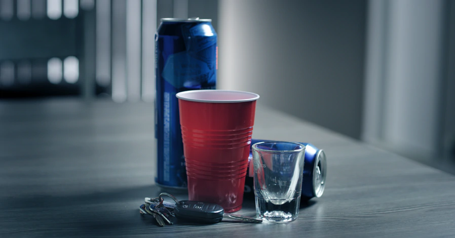 Car Keys on a table next to several beer cans and a red cup, symbolizing a DUI