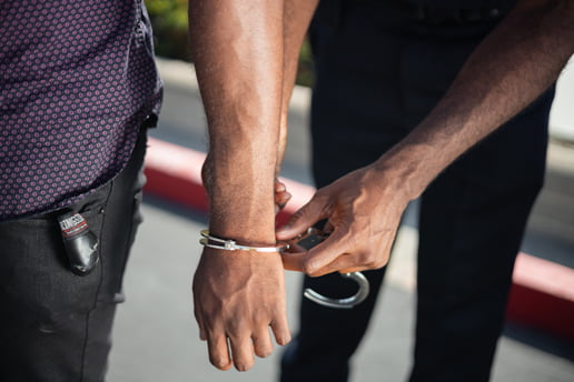 Man being placed under arrest with handcuffs being put around his wrist
