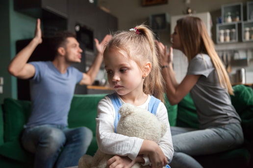Young girl looking sad while her parents are in an argument in the background