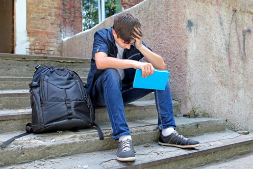 School kid upset sitting on outside steps