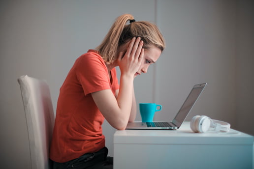 Young woman distraught staring into her laptop