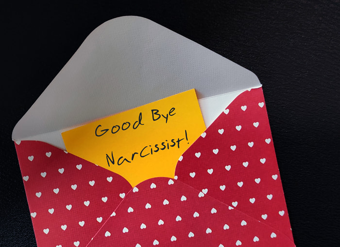 Red letter with hearts on it with a sticky note inside with the phrase 'Good Bye Narcissist!'