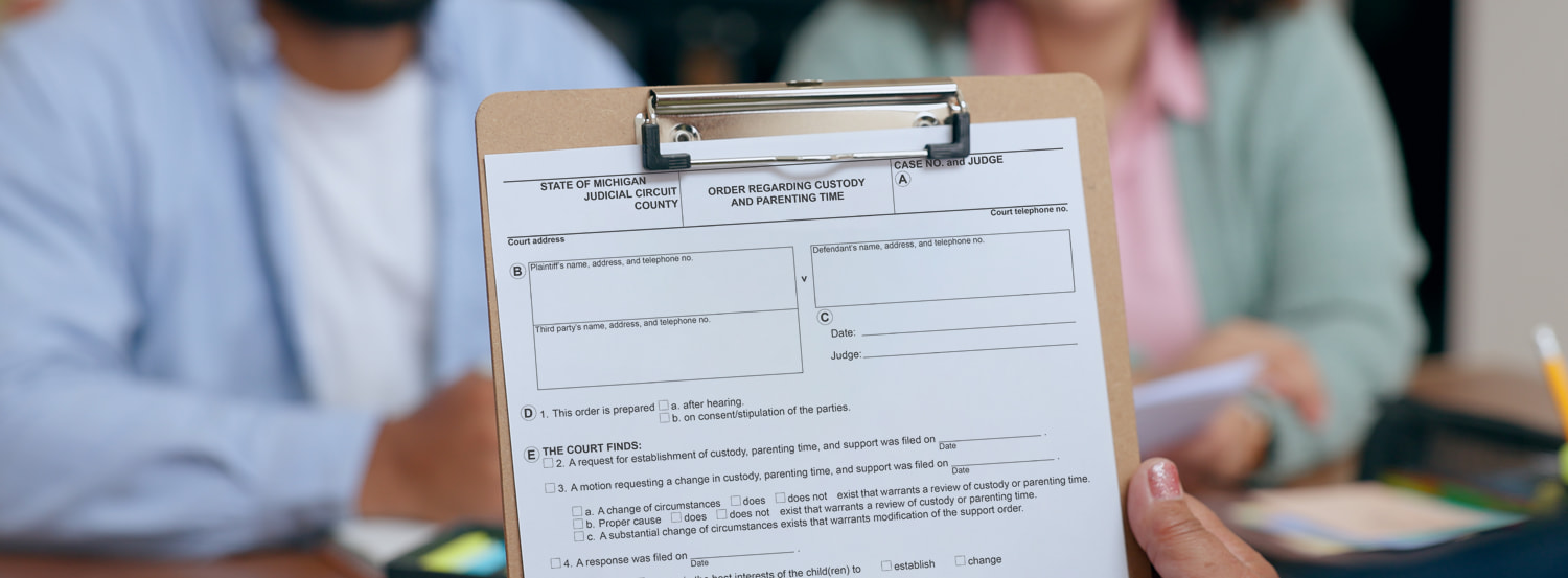 Blank sample of divorce modification forms on a clipboard held by a family law attorney
