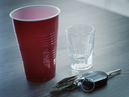 Car keys next to empty shot glass and red solo cup symbolizing a possible DUI